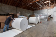 A  sighted worker pushes 1,000-pound rolls of toilet paper towards the production line of toilet paper packets inside the Sirkin Center in San Leandro, CA, on May 11, 2020.